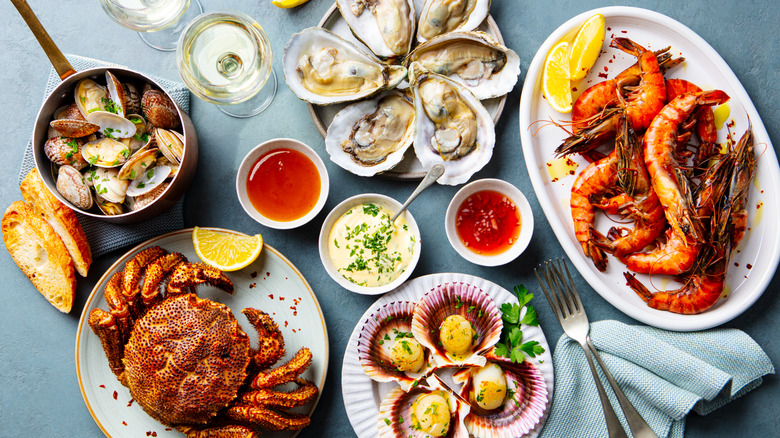 An assortment of plated shrimp, oysters, clams, and crab on a blue background