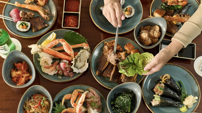 A diner uses chopsticks at The Buffet Hyatt Waikiki to make a lettuce wrap on a table with lots of seafood specialities