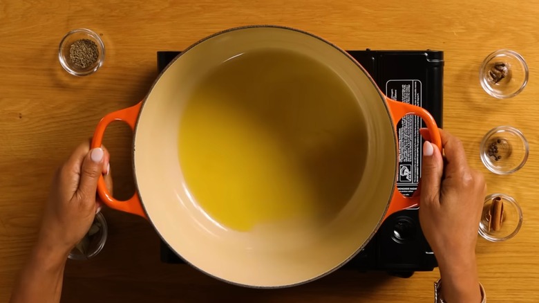 A pair of hands hold a Dutch oven, seen from above, in a still from a Tasty YouTube video