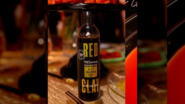 bottle of red clay tresemme hot gloss on a table set for dinner