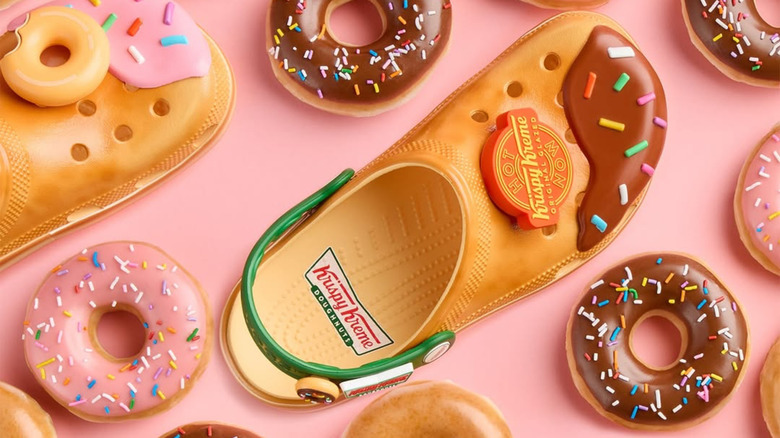 overhead shot of krispy kreme crocs surrounded by donuts on a pink background