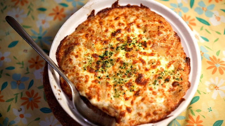 A serving dish of Delmonico potatoes with spoon