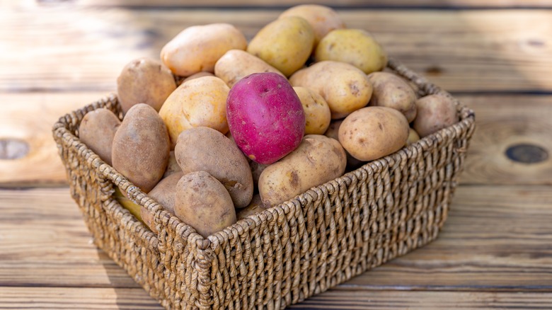 A basket of raw potatoes on wooden table