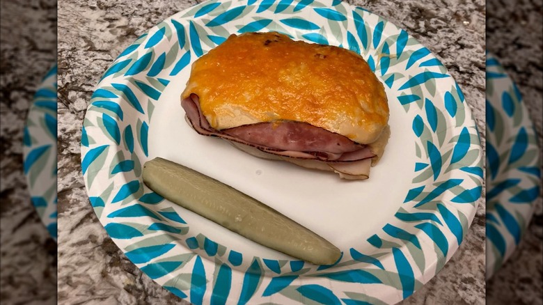 A prosperity sandwich sits on a plate with a pickle slice
