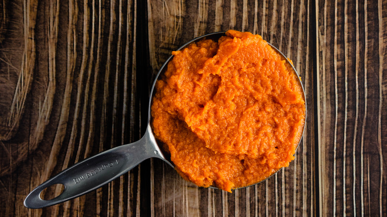 A measuring cup of canned pumpkin purée