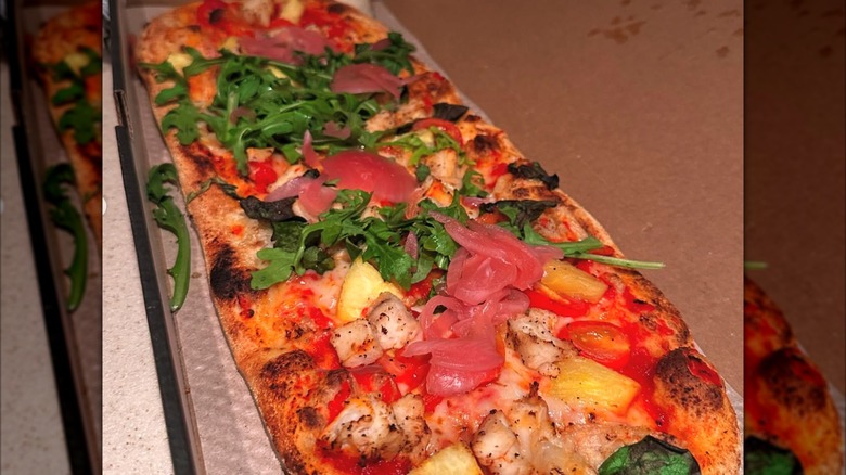 An &pizza pizza, with chicken, pineapple, and onions