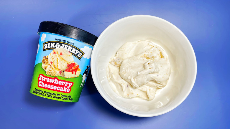 A pint of Strawberry Cheesecake next to a bowl with a scoop