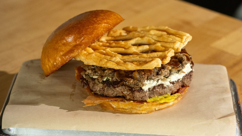 A burger from Hopdoddy Burger Bar on a tray placed on a wooden table
