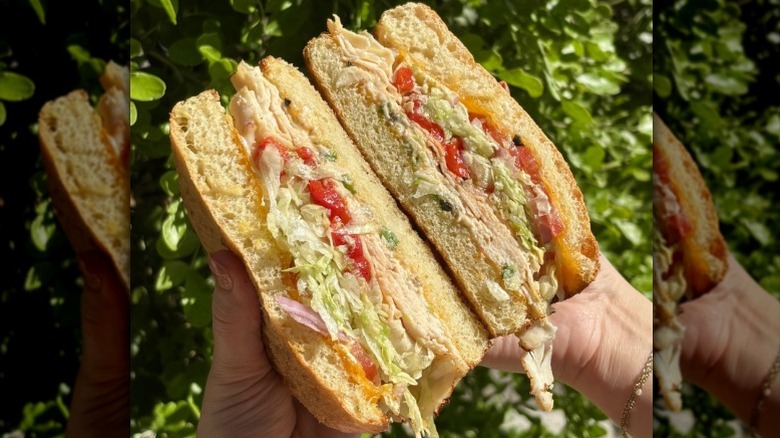 A person holding two halves of a sandwich from Schlotzsky's