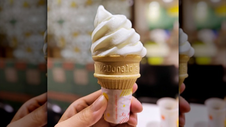 A person holding a vanilla cone from McDonald's