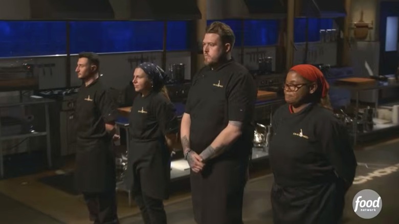 Four "Chopped" contestants in black chef's coats line up on the set of the show