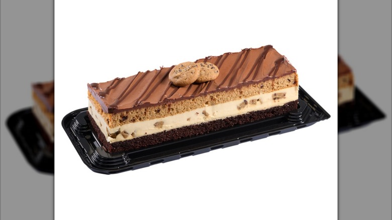 A triple layer cake with chocolate, white mousse, and vanilla layers, topped with chocolate frosting and 2 cookies