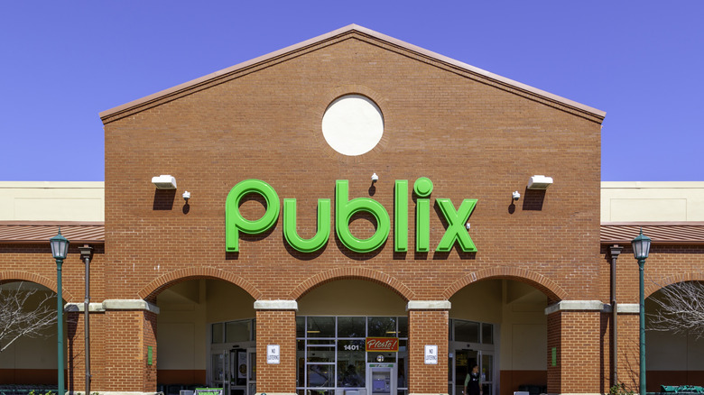 A Publix sign over an entryway on a large brick building under a clear blue sky
