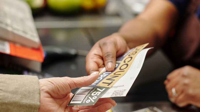 closeup of customer handing coupon to cashier