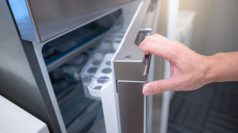 A hand opens a refrigerator door