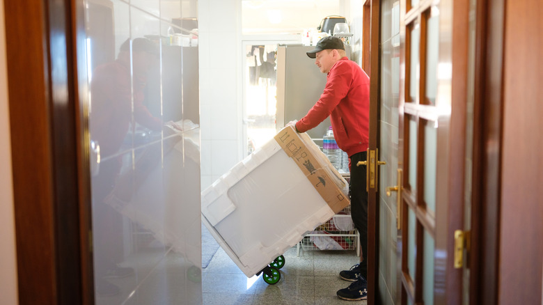 A delivery man delivers a new fridge