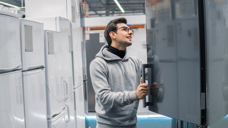 A man looks inside a fridge in a showroom