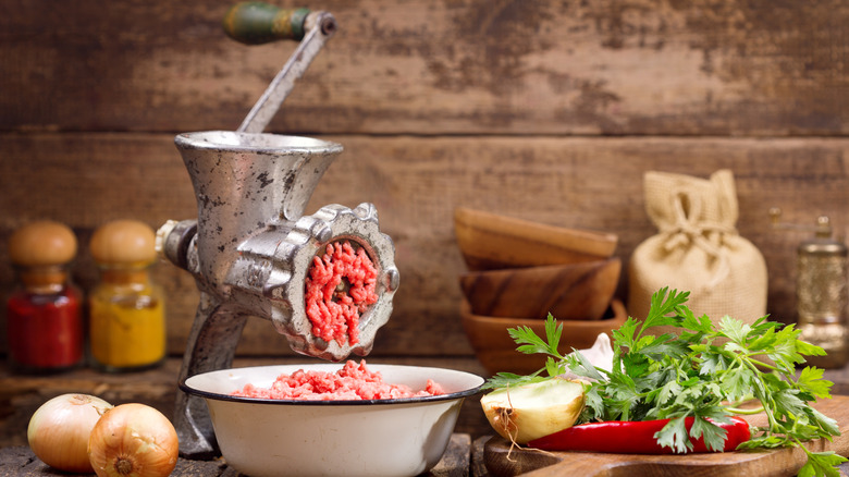 Vintage meat grinder on countertop emptying meat into a bowl