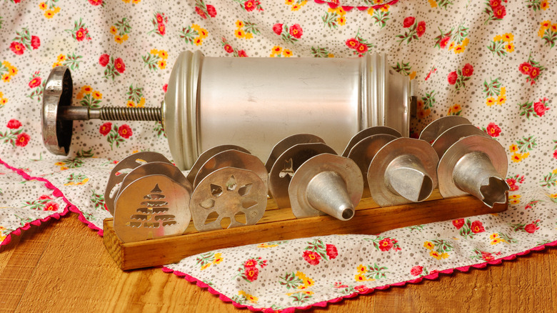 Vintage cookie press and disks laid out on floral fabric