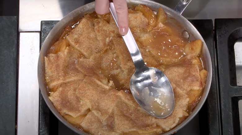 A chef presses a spoon onto an apple pandowdy