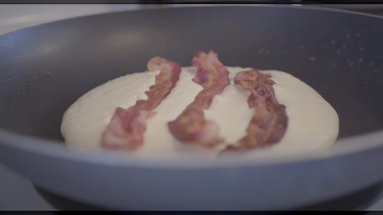Bacon strips resting on top of pancake batter