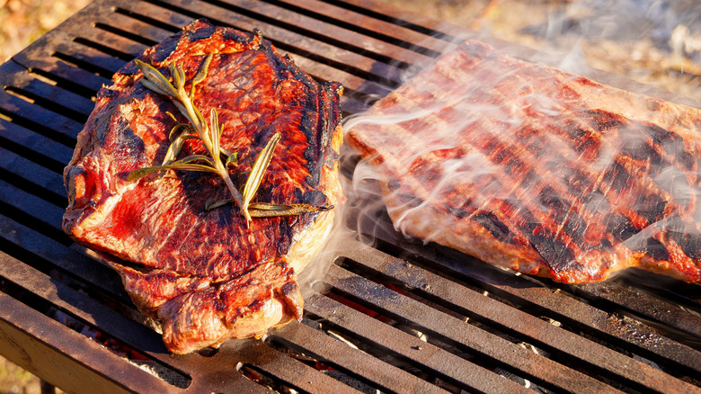 Steaks sizzling and smoking on a hot grill
