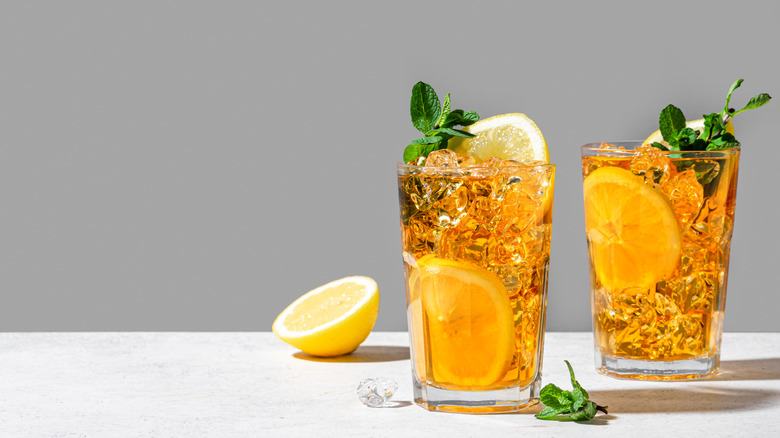 Two glasses of ginger beer, filled with ice, lemon, and mint