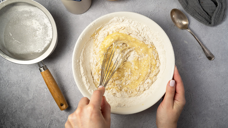 A hand whisking cake ingredients in a bowl