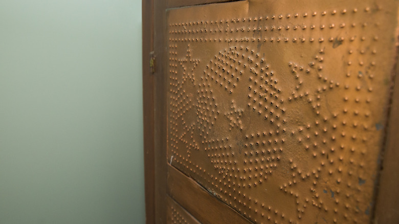 Close-up on the perforated metal siding of a vintage pie safe