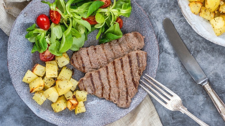 Two slices of minute steak served with potatoes and salad