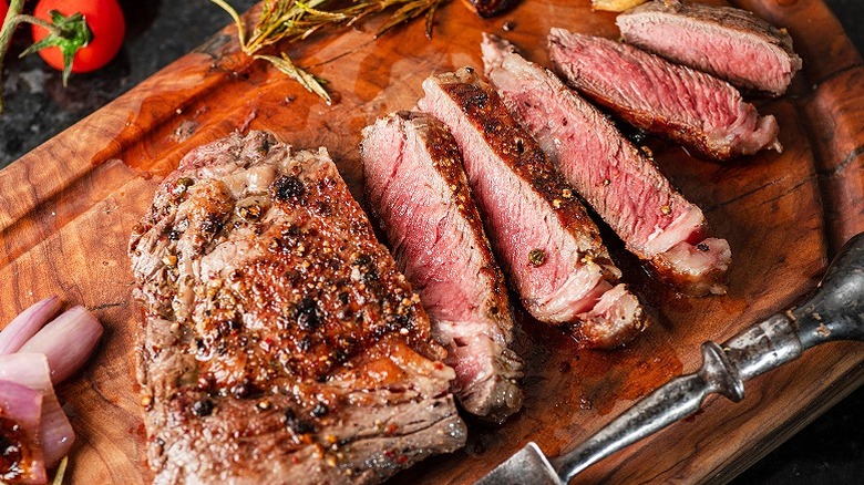 Steak with peppercorn served on a wooden board, cooked medium-rare
