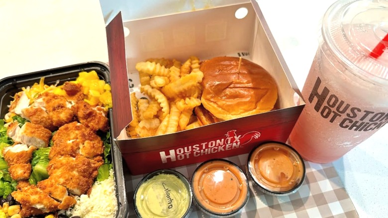 A salad, chicken sandwich, fries, and dips from Houston TX Hot Chicken