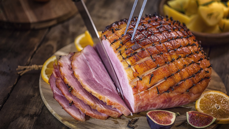 A holiday glazed ham is carved on a dinner table