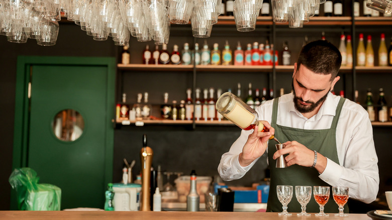 A bartender pours drinks behind a bar