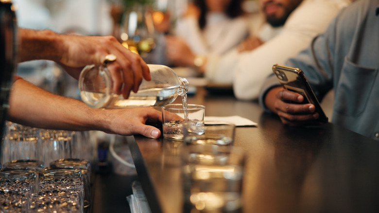 A bartender pours a drink at a bar