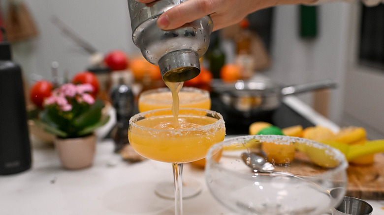 A hand pours a cocktail into a glass