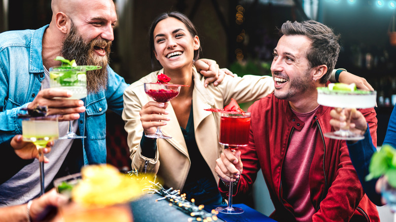 A group of friends laugh while drinking cocktails