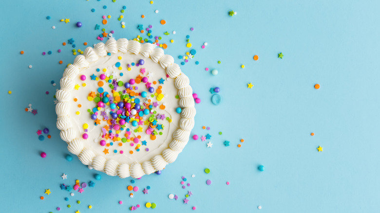 A top-down view of a birthday cake, covered in colorful sprinkles