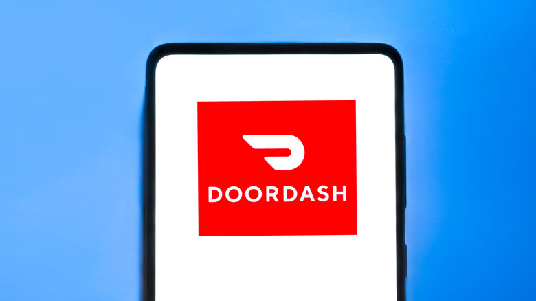 A DoorDash logo is displayed on a smartphone against a blue background