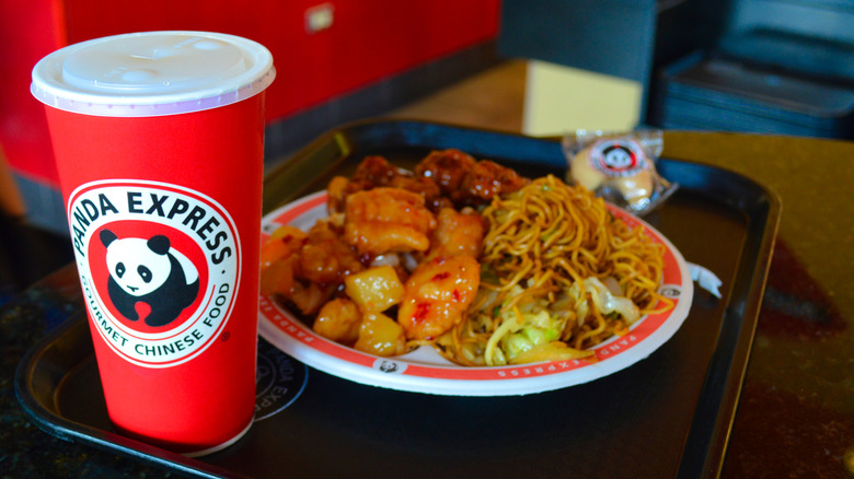 A plate of Panda Express food with a drink next to it