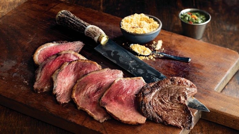 slices of Fogo de Chão meat on wood board with knife