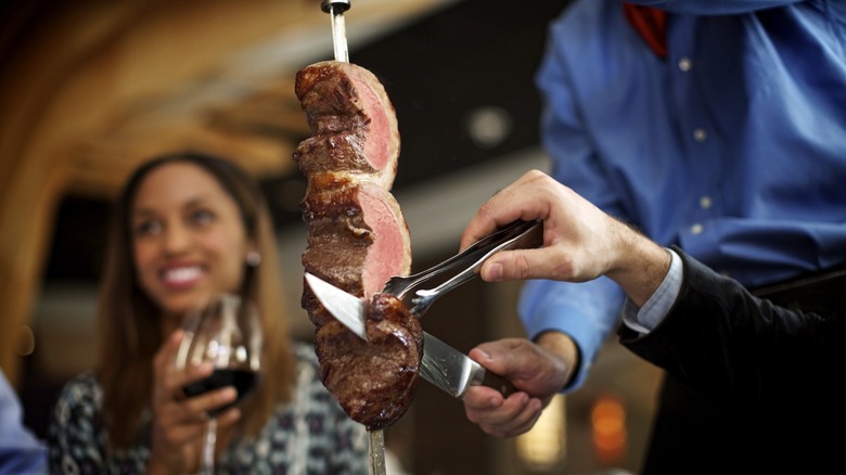 Fogo de Chão diner and meat on skewer