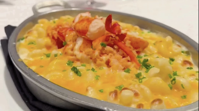 Creamy lobster mac and cheese with tender lobster chunks and melted cheese topping in a serving dish.