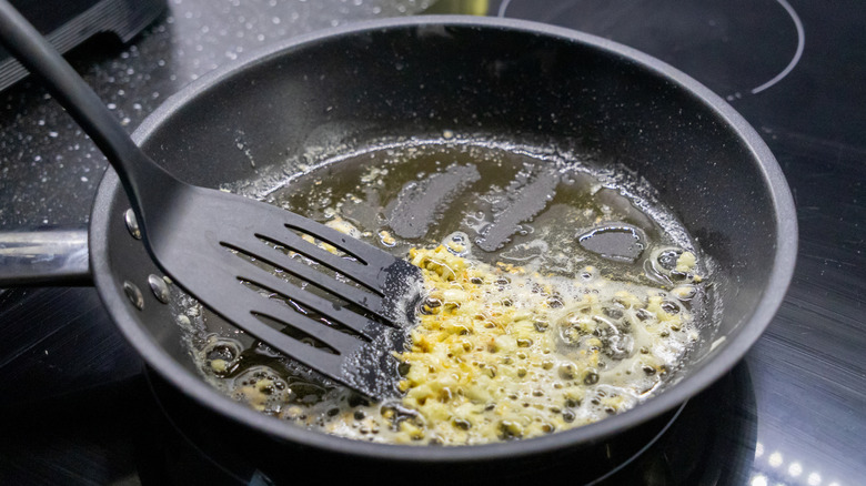 Garlic butter sauce simmering in a pan with a flat spoon