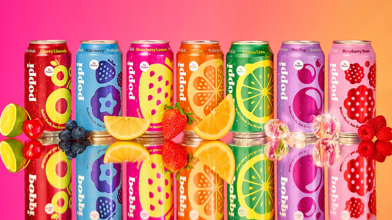 Seven colorful Poppi soda flavors lined up in a row with fruits