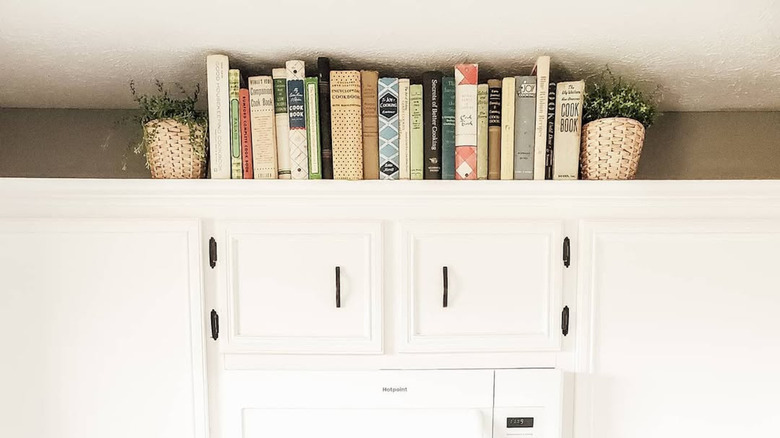 Cookbook collection on top of white kitchen cabinets