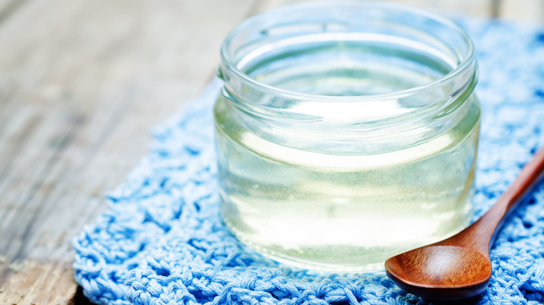 Sugar syrup in a glass jar, placed on a table with a wooden spoon on the side
