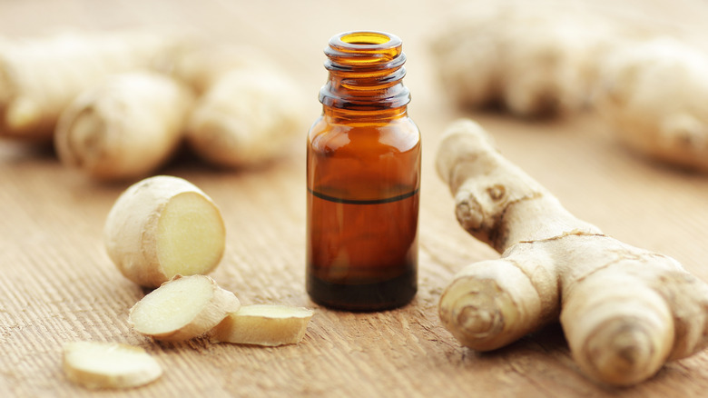Ginger extract in a glass bottle on a wooden table with fresh ginger