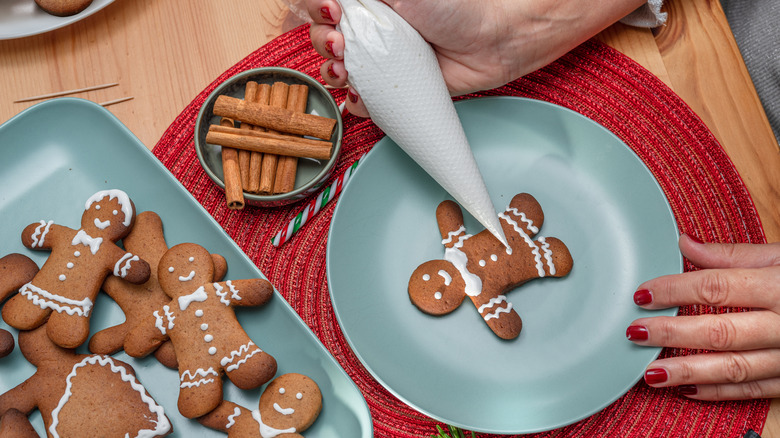 A woman decorating a gingerbread man with royal icing