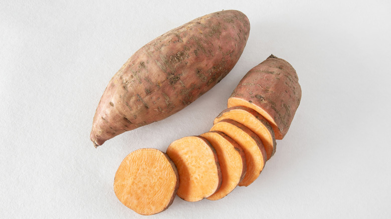 Close up of a whole sweet potato and sliced sweet potato